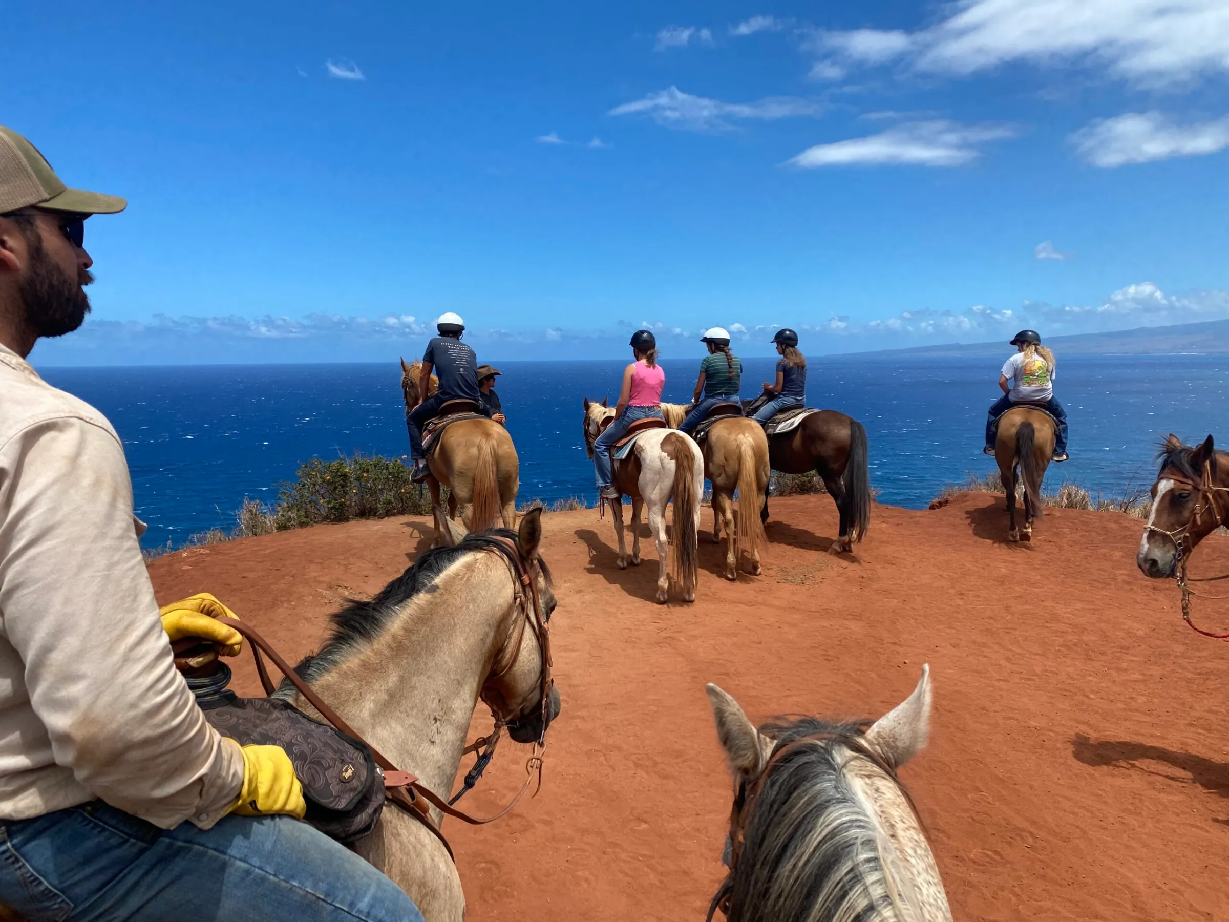 a group of people riding horses on a beach