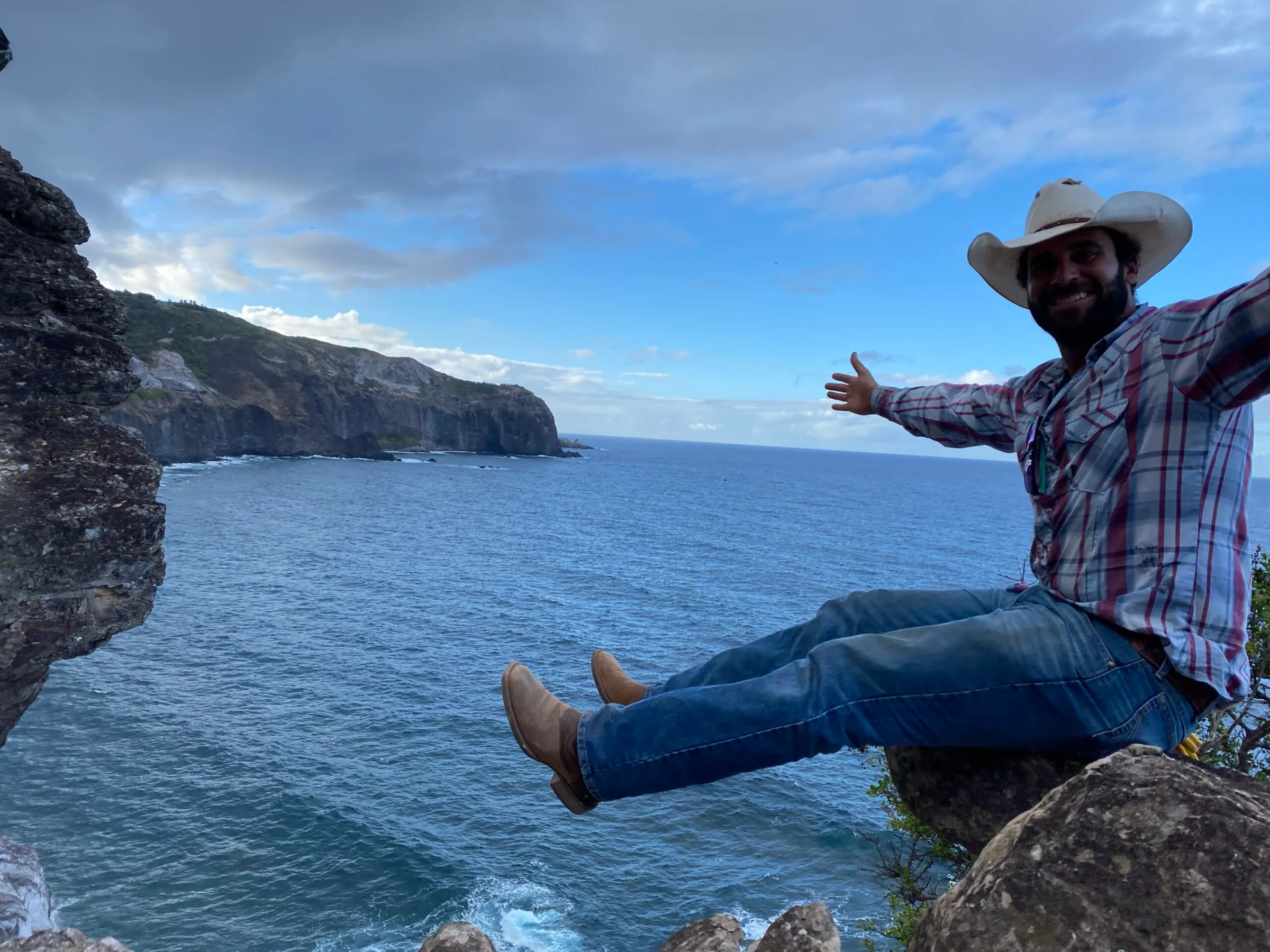a man sitting on a rock next to a body of water